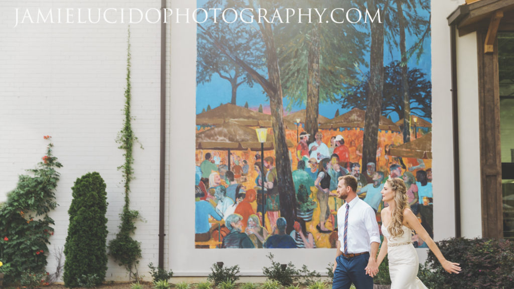 bride and groom walking in front of mural at OMB
